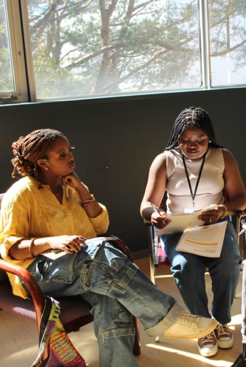 Two young black girls sitting and working on a project indoors.